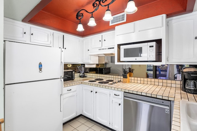 75-6082 Alii Dr Unit A207, Kailua-Kona, HI 96740 - kitchen featuring white appliances, under cabinet range hood, tile counters, and white cabinetry