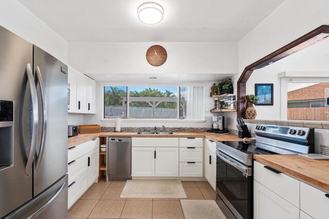 68-1760 Nawili Pl, Waikoloa, HI 96738 - kitchen with stainless steel appliances, butcher block counters, light tile patterned floors, and white cabinetry