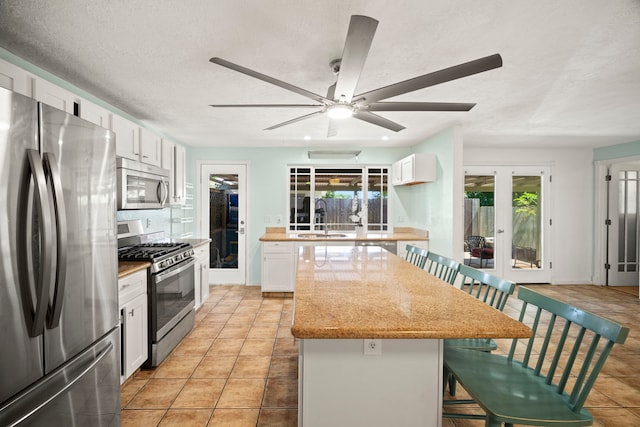 2375 Kipuka St, Koloa, HI 96756 - kitchen featuring stainless steel appliances, a kitchen island, ceiling fan, white cabinetry, and light stone countertops