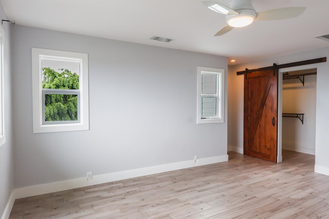 76-206 Kealoha St Unit 2A, Kailua-Kona, HI 96740 - unfurnished bedroom with light wood-style floors, a barn door, and a ceiling fan