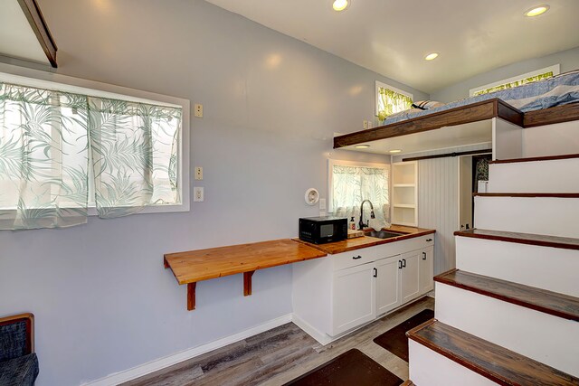 1 Piilani Rd, Pahoa, HI 96778 - kitchen featuring butcher block counters, black microwave, wood finished floors, recessed lighting, and white cabinetry