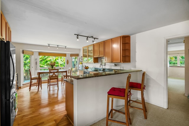 2364-C Hulemalu Rd, Lihue, HI 96766 - kitchen with freestanding refrigerator, open shelves, brown cabinetry, a peninsula, and dark stone countertops