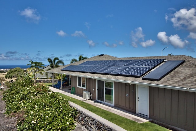 73-4369 Mau Loa Hema Pl, Kailua-Kona, HI 96740 - back of property featuring roof with shingles, solar panels, board and batten siding, and a patio area