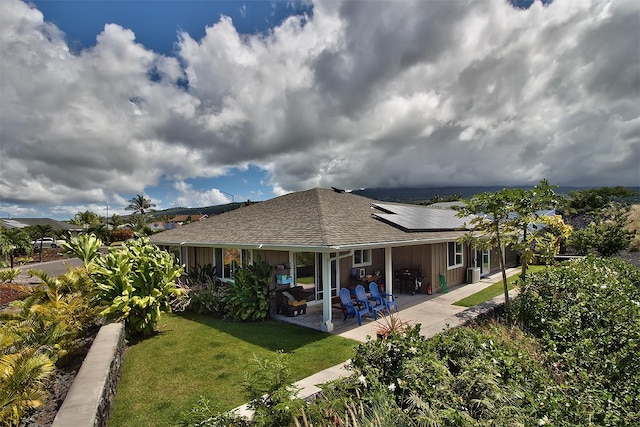 73-4369 Mau Loa Hema Pl, Kailua-Kona, HI 96740 - back of property with roof mounted solar panels, a patio area, a lawn, and a shingled roof