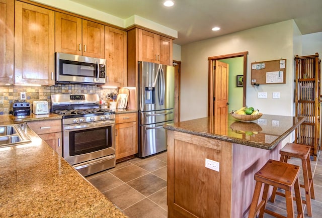 39 Kula Pl Unit 1, Hilo, HI 96720 - kitchen featuring appliances with stainless steel finishes, a breakfast bar area, recessed lighting, backsplash, and dark stone counters