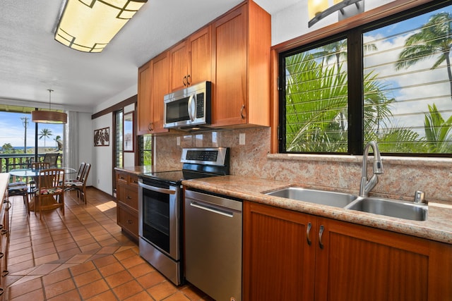 1870 Hoone Rd Unit 511, Koloa, HI 96756 - kitchen with stainless steel appliances, decorative backsplash, brown cabinetry, tile patterned floors, and hanging light fixtures