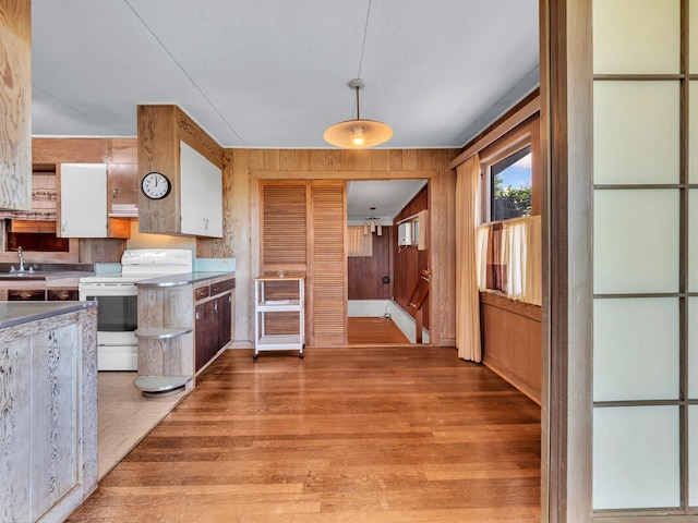 196 Iwalani St, Hilo, HI 96720 - kitchen with electric stove, light wood-type flooring, wooden walls, white cabinets, and decorative light fixtures