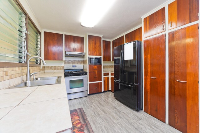 81-6356 Keopuka Pl, Captain Cook, HI 96750 - kitchen with freestanding refrigerator, stainless steel gas stove, under cabinet range hood, built in microwave, and backsplash