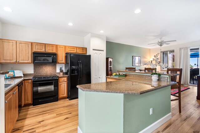 75-5919 Alii Dr Unit M3, Kailua-Kona, HI 96740 - kitchen featuring black appliances, a kitchen bar, light wood-style flooring, a ceiling fan, and tasteful backsplash