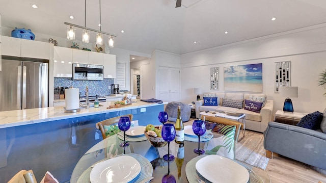 2253 Poipu Rd Unit 216, Koloa, HI 96756 - kitchen featuring stainless steel appliances, light wood-style floors, white cabinets, decorative backsplash, and hanging light fixtures