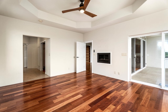 79-1145 Kao Rd, Holualoa, HI 96725 - unfurnished bedroom featuring wood finished floors, a raised ceiling, a glass covered fireplace, and ceiling fan