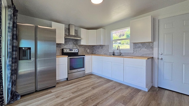 48-5241 Kukuihaele Rd, Honokaa, HI 96727 - kitchen featuring stainless steel appliances, wall chimney range hood, light wood-style flooring, and white cabinetry