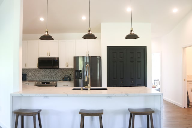 15-1393 29th Ave, Keaau, HI 96749 - kitchen with appliances with stainless steel finishes, decorative backsplash, white cabinets, a breakfast bar, and wood finished floors