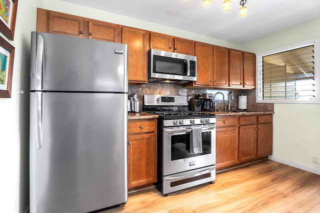 75-6008 Alii Dr Unit 219, Kailua-Kona, HI 96740 - kitchen with appliances with stainless steel finishes, light wood-type flooring, tasteful backsplash, and brown cabinets