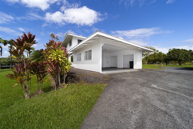 17-436 Ipuaiwaha St, Keaau, HI 96749 - view of side of home featuring driveway, an attached carport, and a lawn
