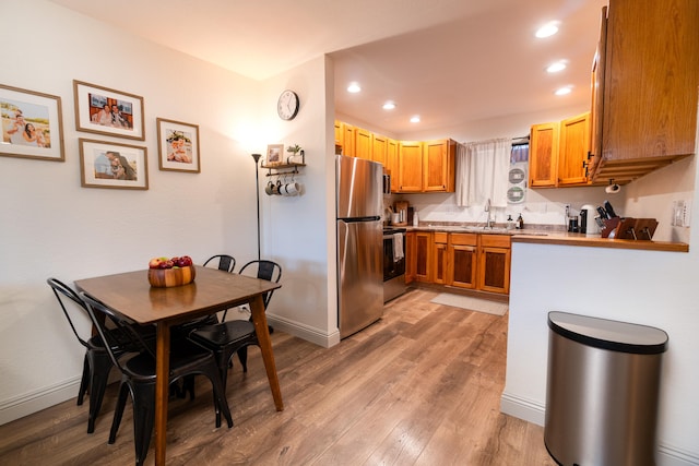 75-5863 Kuakini Hwy Unit 104, Kailua-Kona, HI 96740 - kitchen with stainless steel appliances, light wood-style flooring, brown cabinetry, recessed lighting, and light countertops