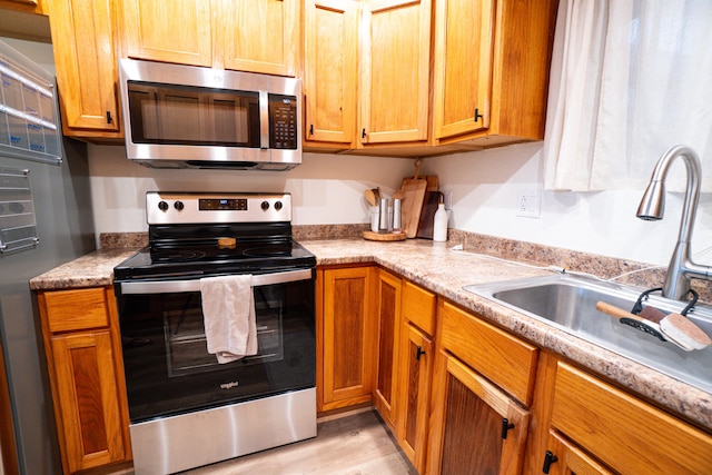 75-5863 Kuakini Hwy Unit 104, Kailua-Kona, HI 96740 - kitchen featuring stainless steel appliances, light countertops, brown cabinetry, and light wood finished floors