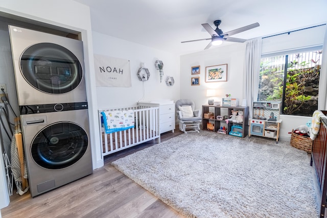 75-5863 Kuakini Hwy Unit 104, Kailua-Kona, HI 96740 - bedroom with stacked washing machine and dryer, wood finished floors, a crib, and ceiling fan