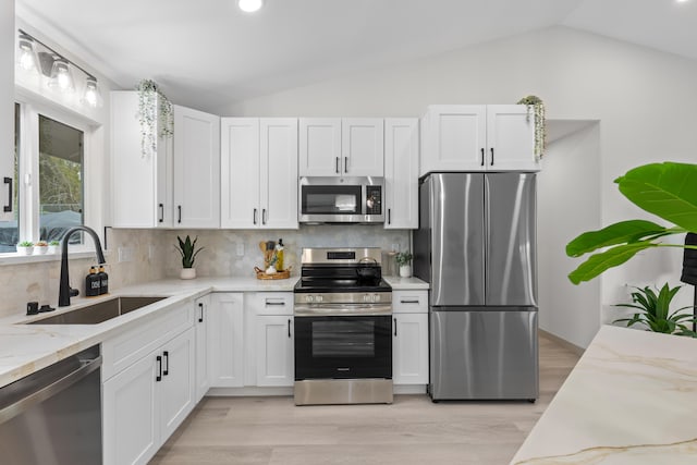 16-2110 Tangerine Dr, Pahoa, HI 96778 - kitchen featuring stainless steel appliances, vaulted ceiling, white cabinetry, decorative backsplash, and light stone counters