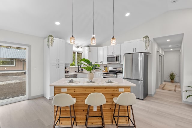 16-2110 Tangerine Dr, Pahoa, HI 96778 - kitchen with appliances with stainless steel finishes, lofted ceiling, light wood-type flooring, white cabinets, and a breakfast bar
