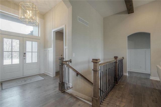 entryway featuring a chandelier, dark wood-type flooring, and beamed ceiling