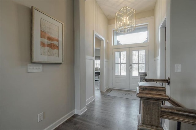 foyer featuring french doors, dark wood-type flooring, and a chandelier