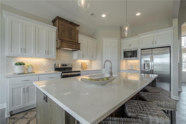 kitchen with pendant lighting, a kitchen island with sink, and appliances with stainless steel finishes