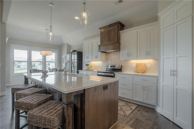 kitchen with dark hardwood / wood-style flooring, a breakfast bar area, white cabinetry, an island with sink, and stainless steel electric stove