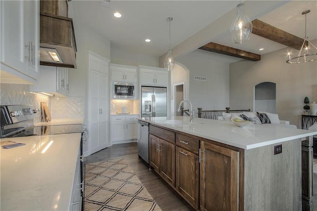 kitchen with white cabinets, appliances with stainless steel finishes, and an island with sink