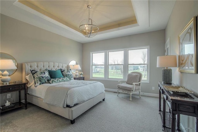 carpeted bedroom with an inviting chandelier and a tray ceiling