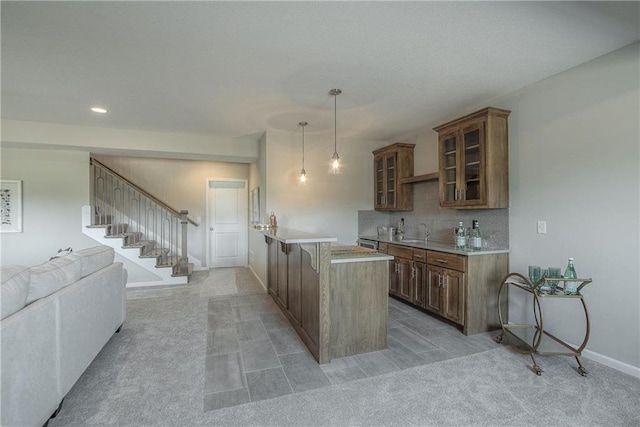 kitchen with backsplash, light colored carpet, pendant lighting, and sink