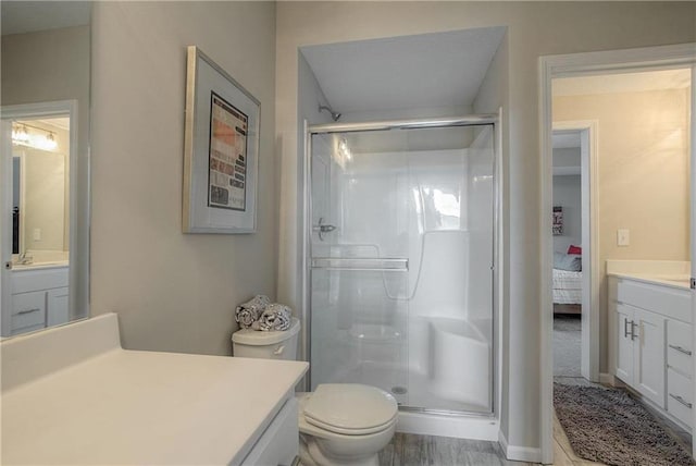 bathroom featuring a shower with door, toilet, and vanity