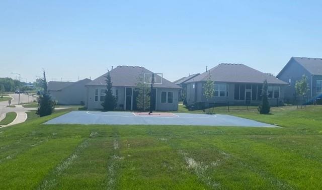 back of property with a yard and basketball hoop