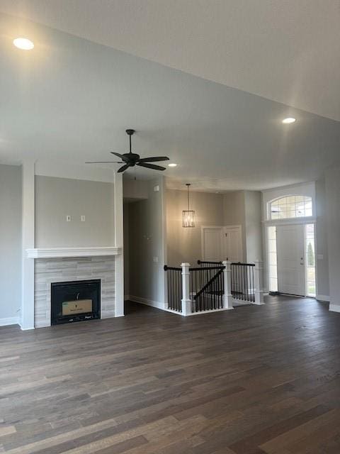 unfurnished living room featuring ceiling fan, dark wood-type flooring, and a fireplace