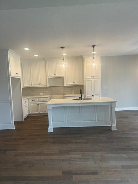 kitchen featuring tasteful backsplash, dark wood-type flooring, pendant lighting, sink, and a kitchen island with sink