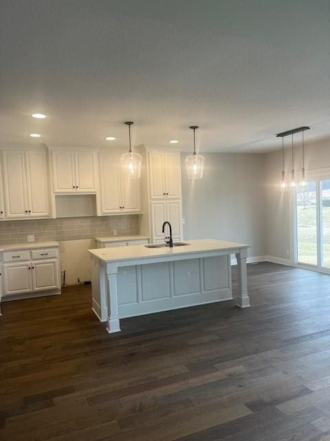 kitchen featuring white cabinetry, sink, pendant lighting, and a kitchen island with sink