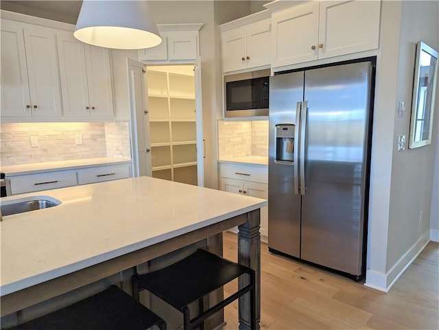 kitchen with black microwave, stainless steel refrigerator with ice dispenser, backsplash, and white cabinetry