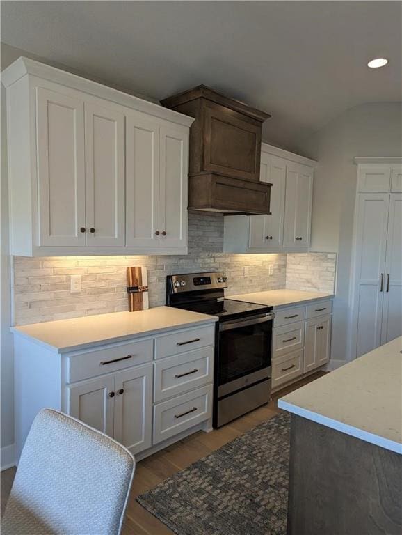 kitchen featuring vaulted ceiling, light wood-type flooring, white cabinets, stainless steel electric stove, and backsplash