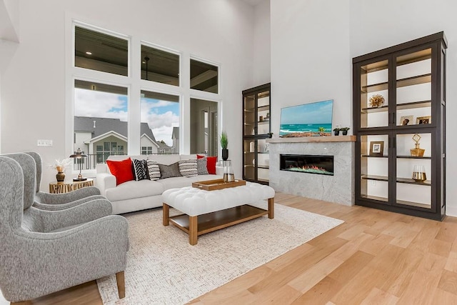 living room with a fireplace, a towering ceiling, and hardwood / wood-style floors