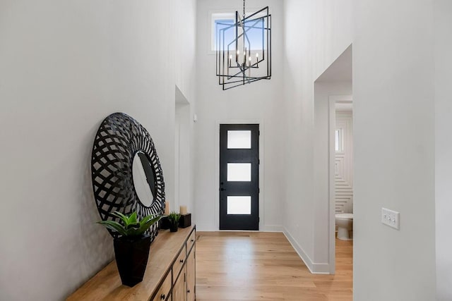 foyer entrance featuring a notable chandelier, a towering ceiling, and light hardwood / wood-style floors