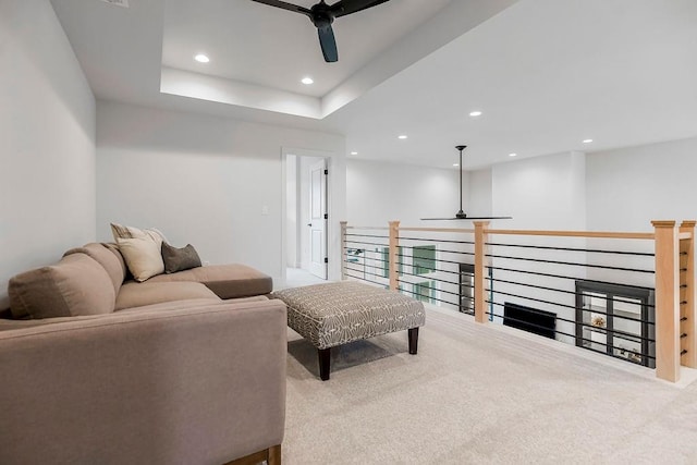 living room with light carpet, a tray ceiling, and ceiling fan