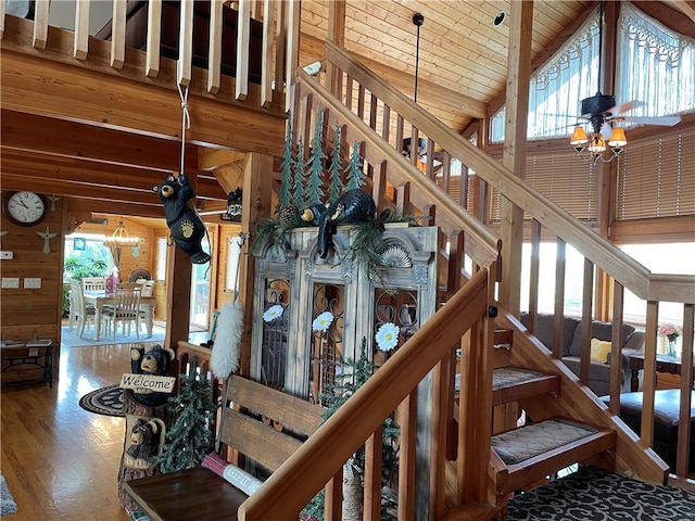 stairway with ceiling fan, hardwood / wood-style flooring, wooden ceiling, high vaulted ceiling, and wooden walls