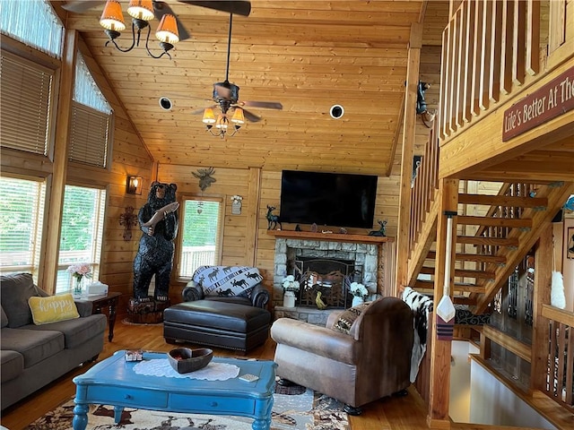 living room with a stone fireplace, wood ceiling, hardwood / wood-style floors, high vaulted ceiling, and wood walls