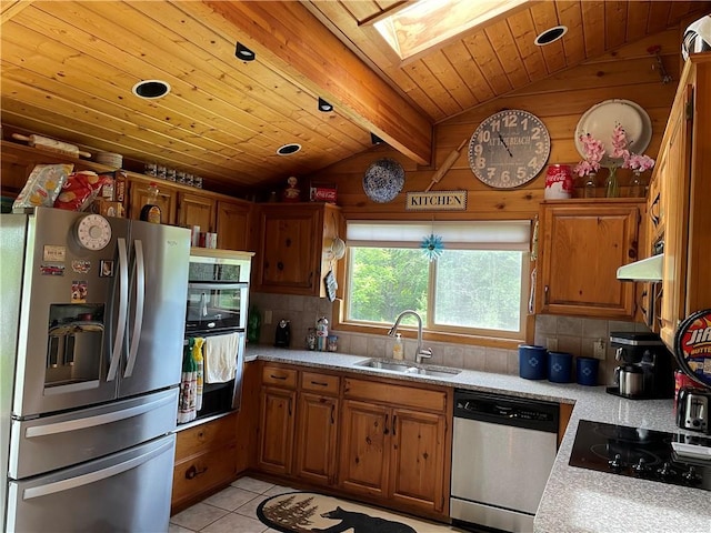 kitchen featuring sink, appliances with stainless steel finishes, vaulted ceiling with skylight, and tasteful backsplash