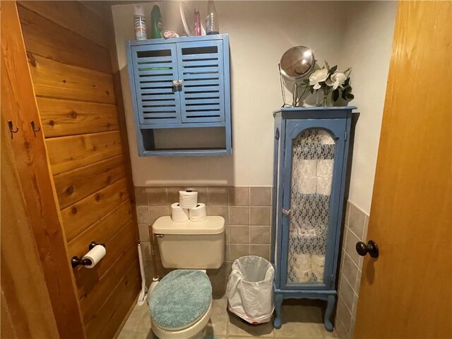 bathroom with toilet and tile walls