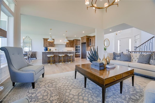 living room with a high ceiling, light wood-type flooring, and an inviting chandelier