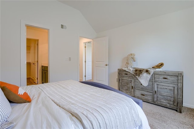 bedroom with ensuite bath, light carpet, and high vaulted ceiling