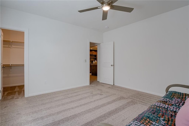 unfurnished bedroom featuring carpet, a walk in closet, ceiling fan, and a closet