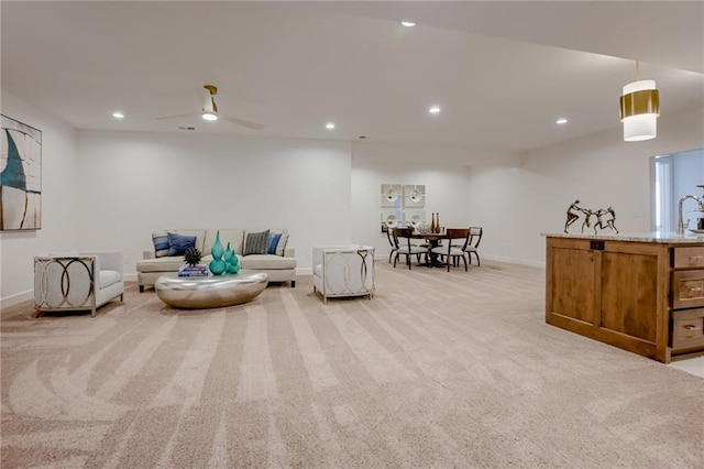 living area with ceiling fan and light colored carpet