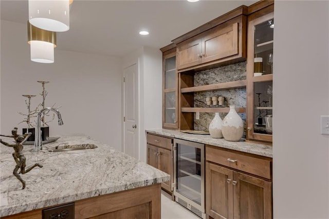 bar with beverage cooler, decorative light fixtures, light stone counters, and sink